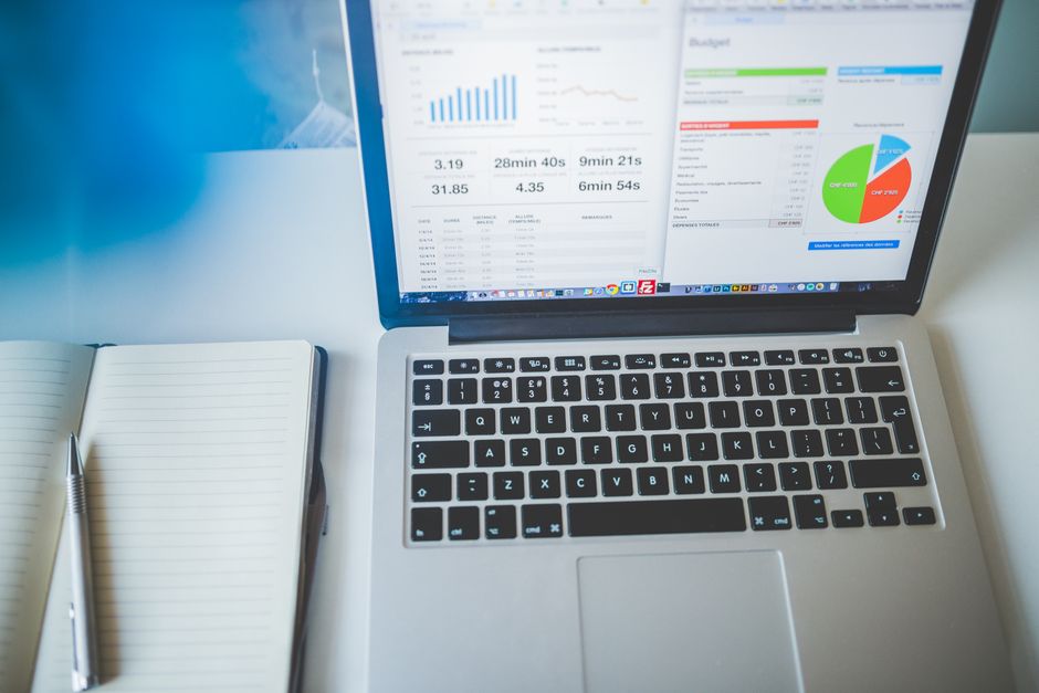 Laptop displaying charts and graphs next to a notebook, ideal for business and tech themes.