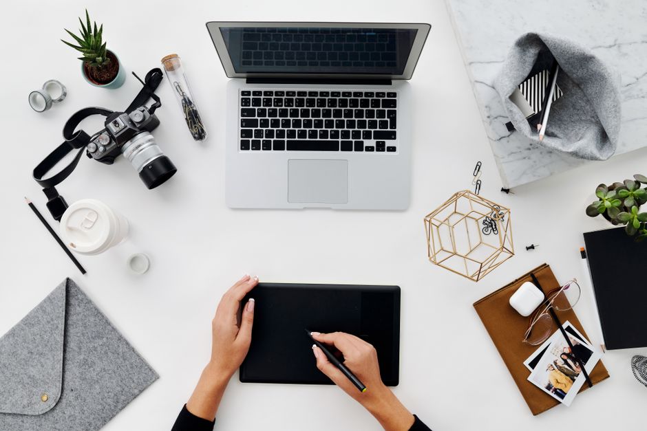 Overhead shot of a modern workspace with laptop, tablet, and camera for creative professionals.