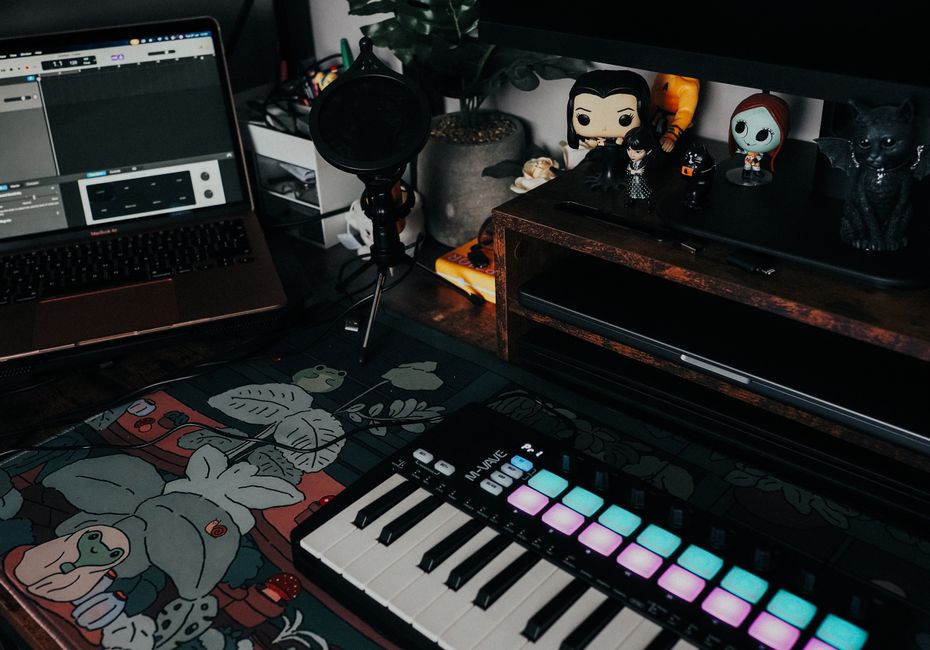 Stylish home recording setup featuring a laptop, MIDI keyboard, and character figurines for creative inspiration.