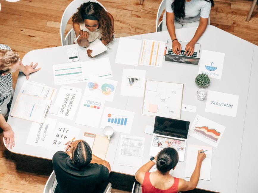 Top view of a diverse team collaborating on marketing strategies around a white table.